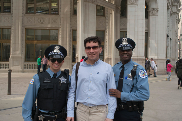 A young man stands on a Chicago street between two police officers, one of whom is black.