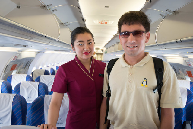 A young man stands onboard A321 in the aisle next to a slender Chinese girl dressed in China Southern Airlines uniform