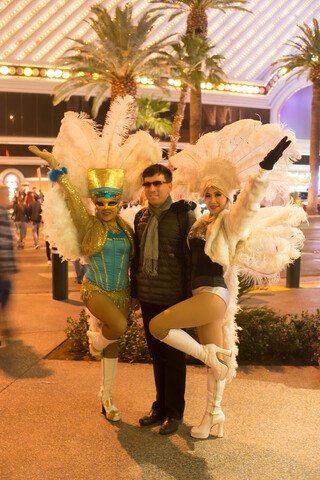 A young man stands on the street in Las Vegas between two provocatively dressed girls.